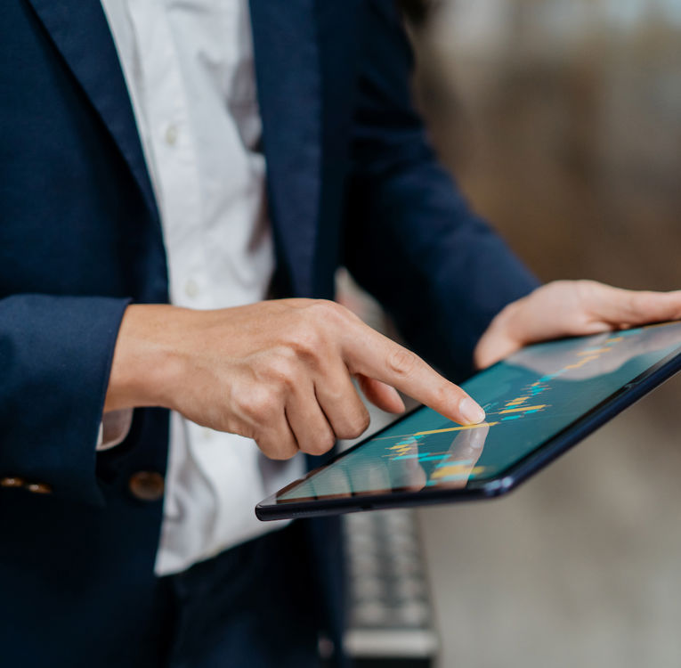 Business professional in a suit analyzing data on a tablet with an interactive chart.