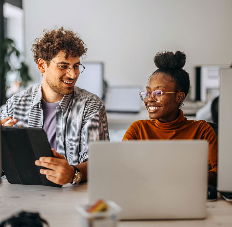Two colleagues in an office collaborating on workforce management, scheduling, and time tracking using digital tools