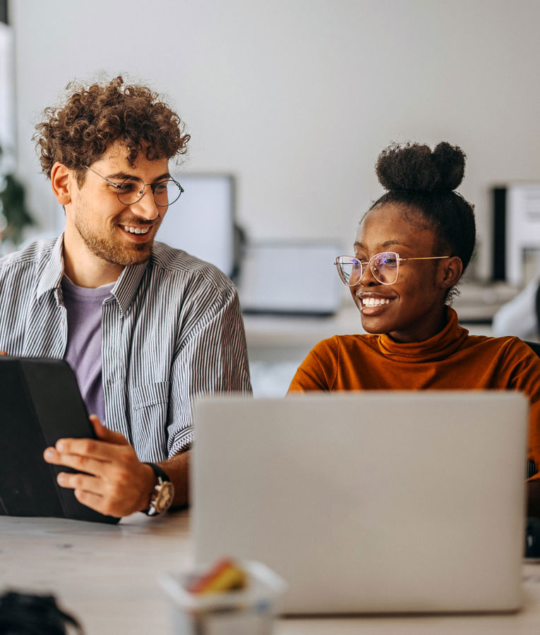 Two colleagues in an office collaborating on workforce management, scheduling, and time tracking using digital tools