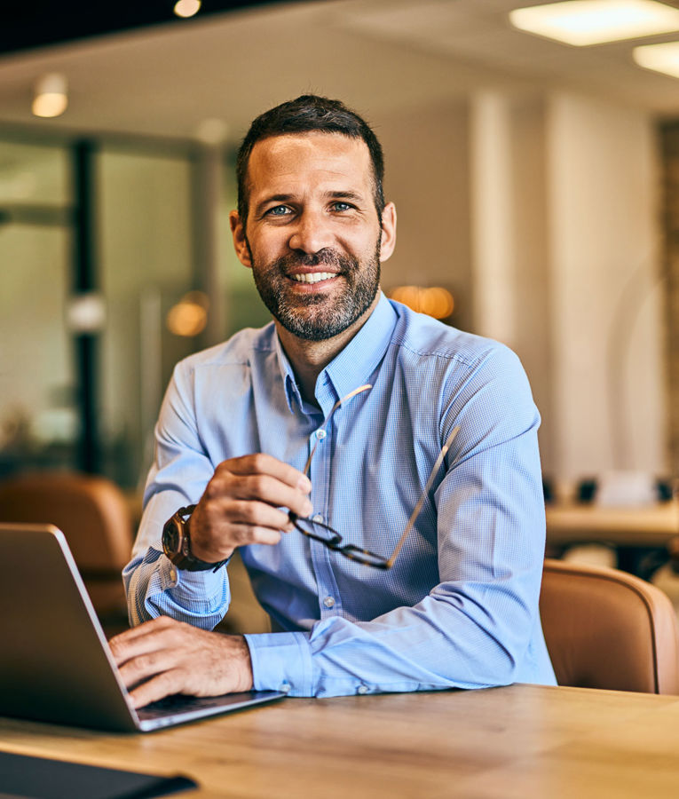 Professional man in an office setting with a laptop, representing modern workforce management and productivity.