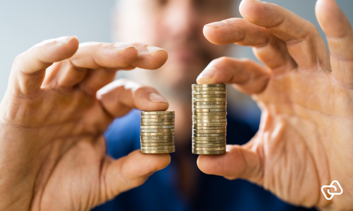 A person holds two stacks of coins of different heights, illustrating the pay differences addressed by the EU Pay Transparency Directive.