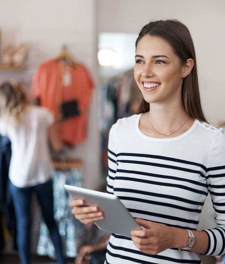 A confident fashion store manager reviewing inventory and engaging with employees to optimize operations.