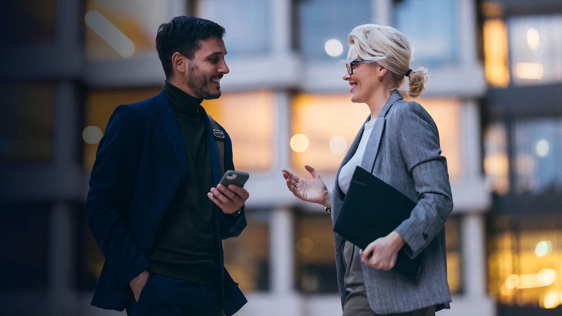 Two colleagues in a business setting discussing workforce planning and effective employee management using a mobile device.