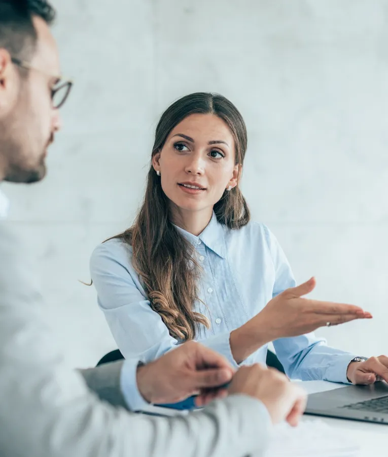 Forretningsfolk drøfter arbejdsstyrkestrategier på et moderne kontor og bruger en bærbar computer til digitalt samarbejde og planlægning.