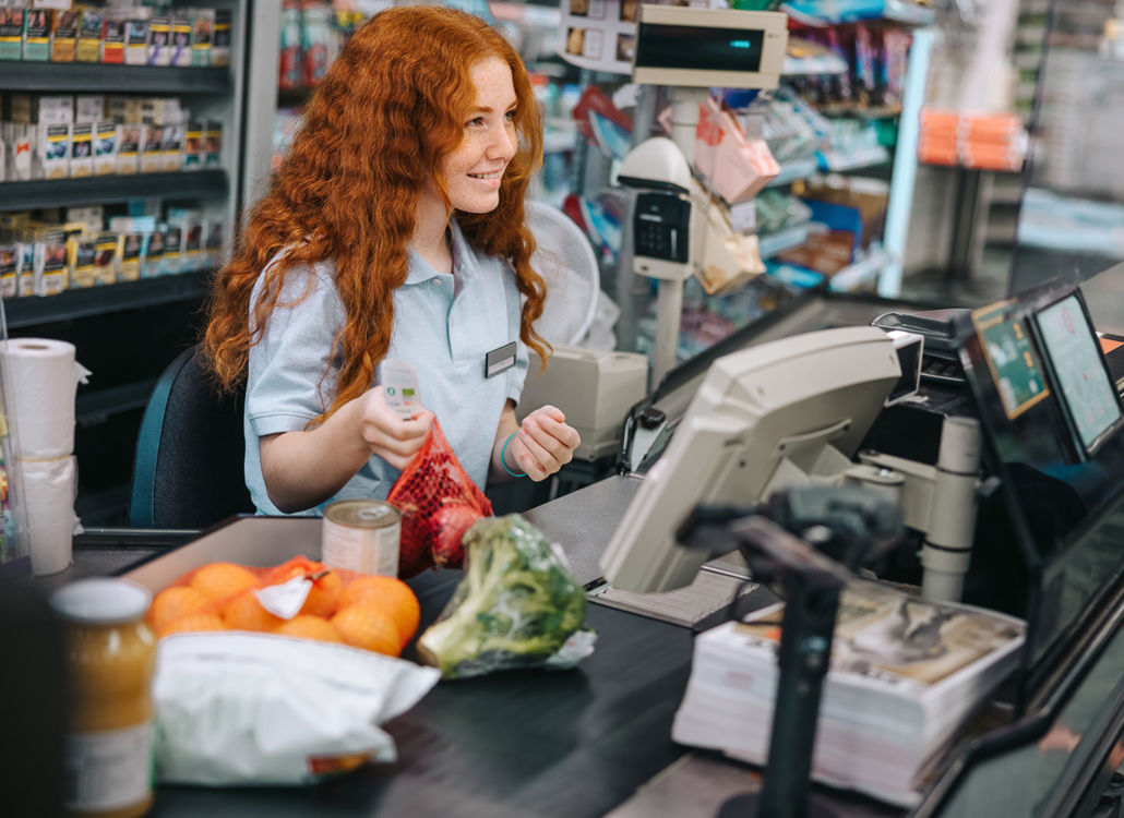 A supermarket cashier scanning items at checkout while assisting a customer, ensuring a fast and seamless shopping experience.