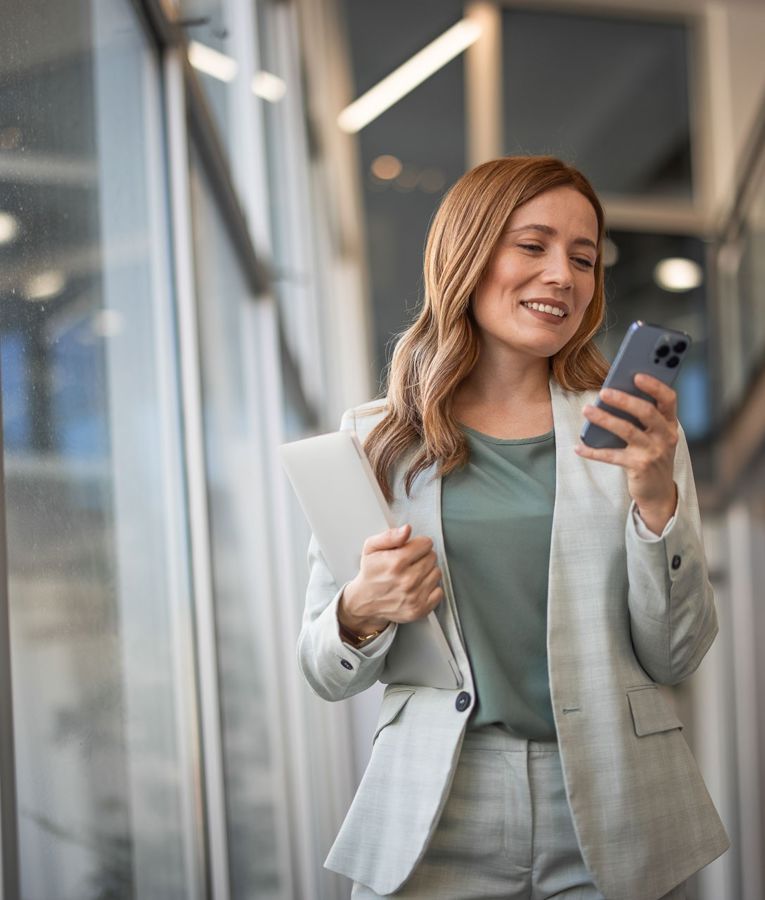Professional woman in a modern business setting using her smartphone for workforce management, scheduling, and time tracking